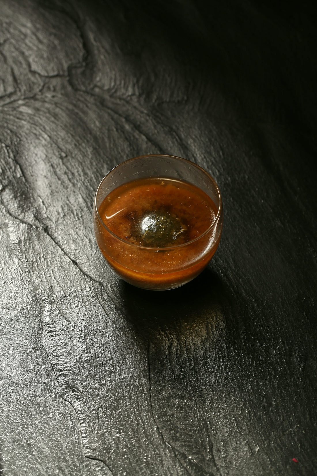 a small bowl of sauce on a black surface
