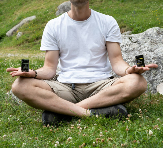 a man sitting in the grass with two cups in his hands