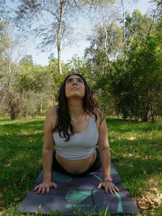 Woman doing cobra pose yoga on mat outdoors